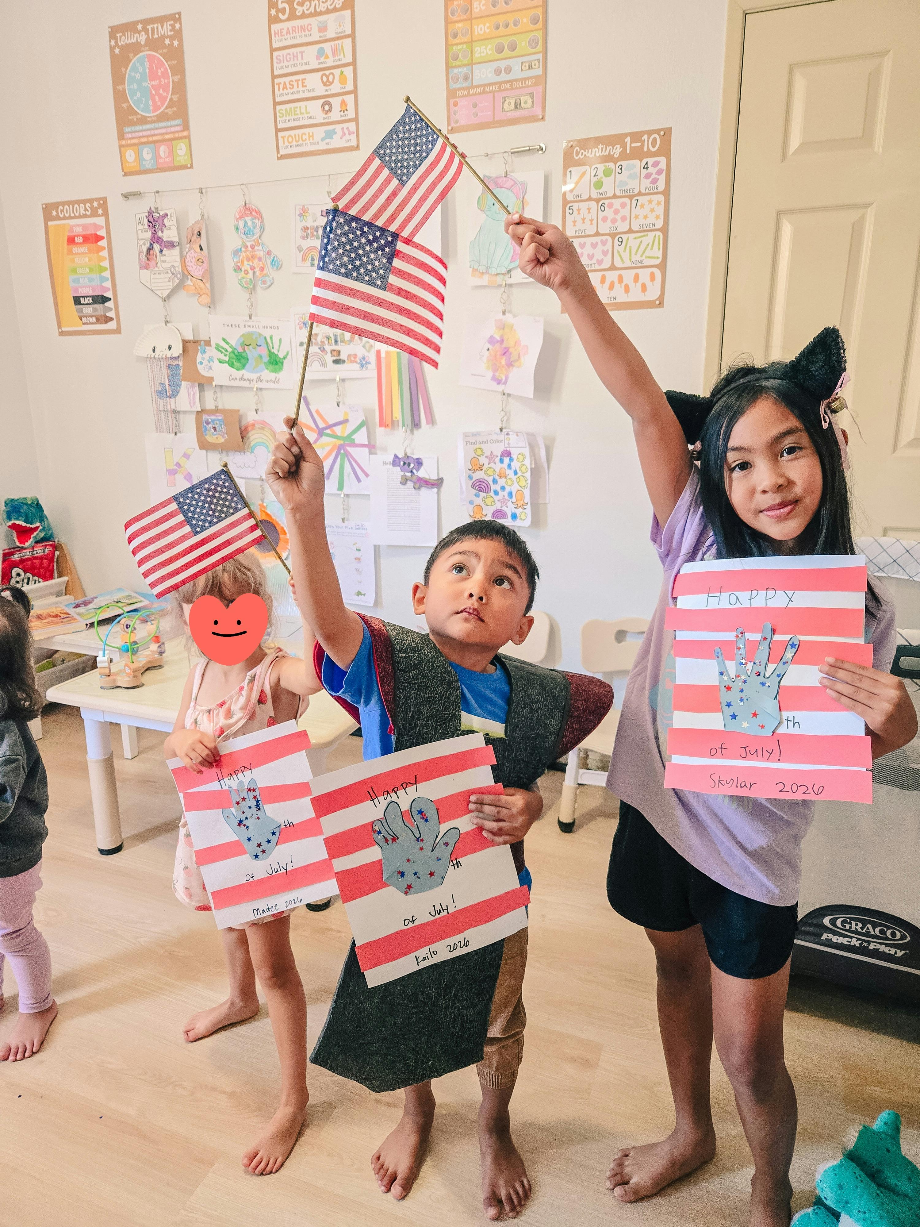 Three children holding American flags and handmade Fourth of July crafts