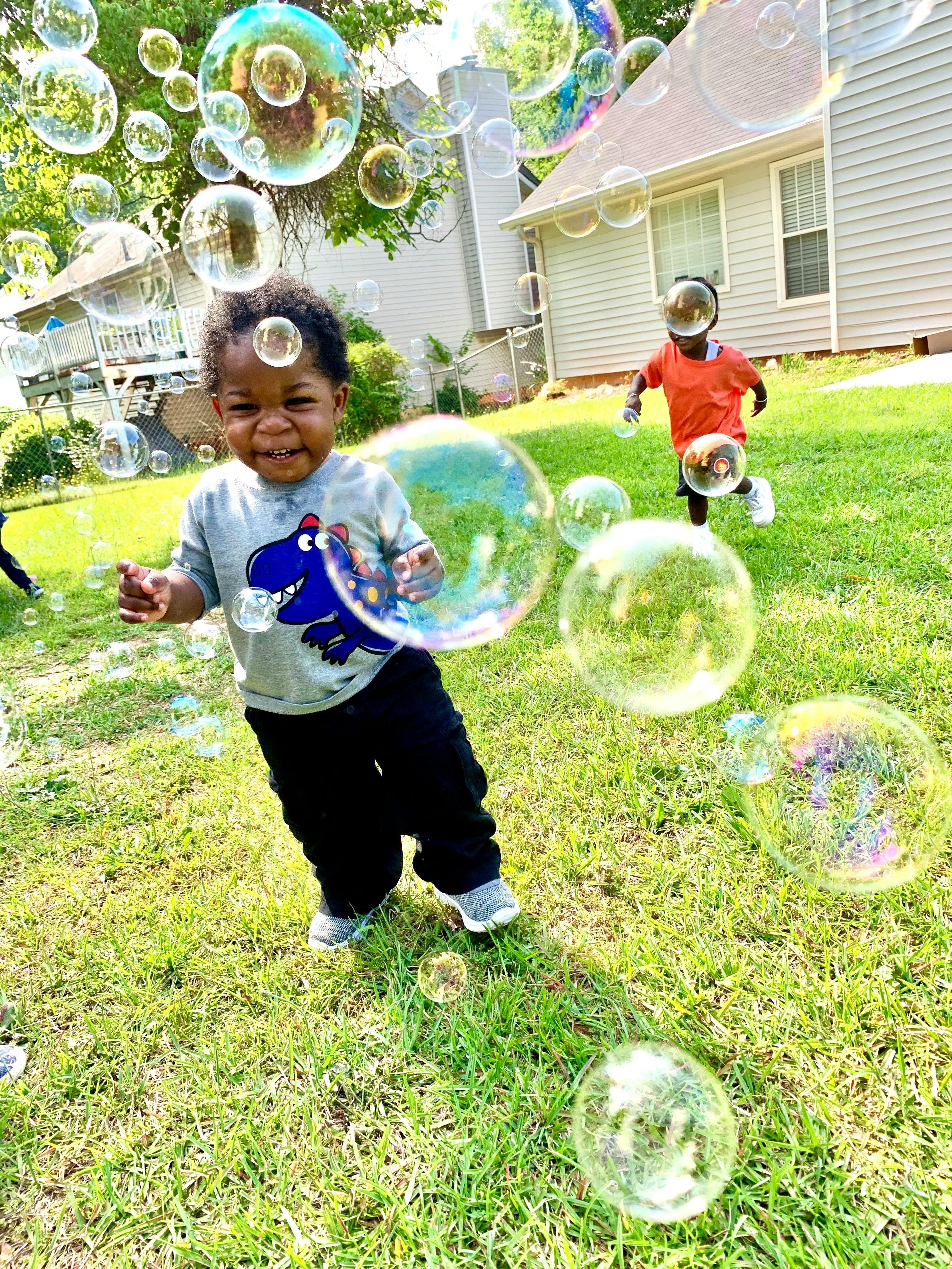 Child playing with bubbles in a grassy yard
