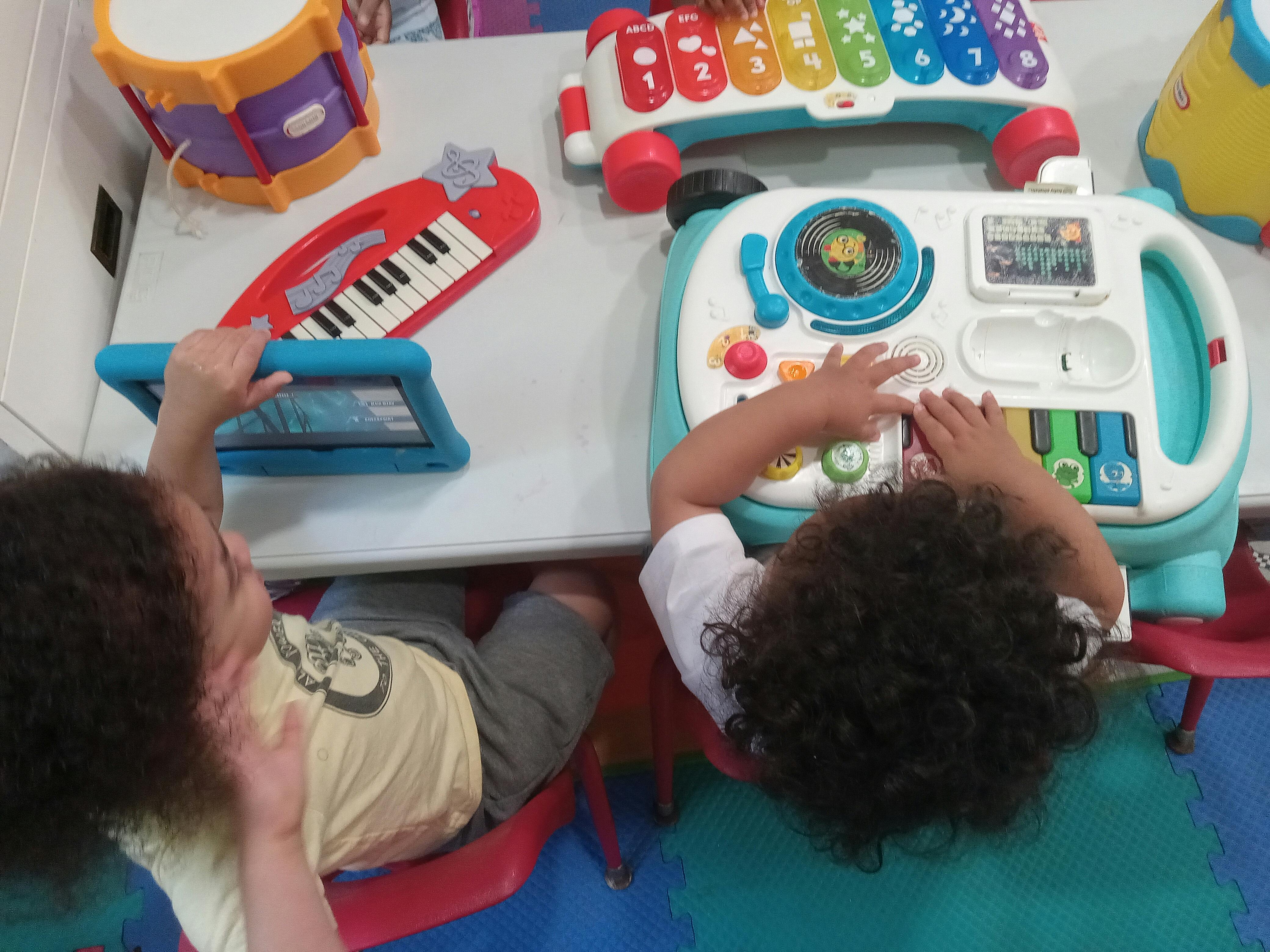 Two children playing with musical toys at a table