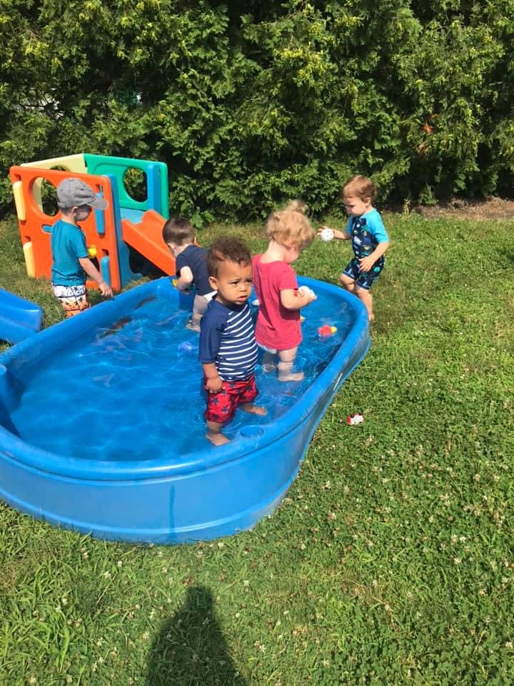 Children playing in a small blue wading pool outdoors
