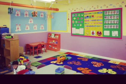 Child in a classroom with colorful rug and learning charts