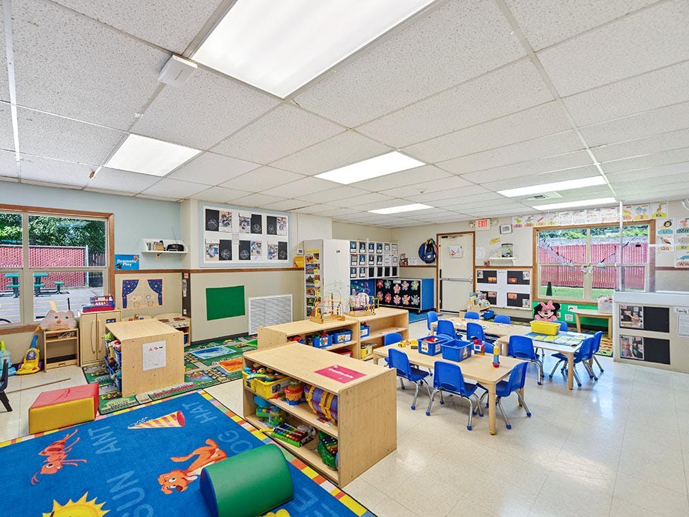 Empty colorful preschool classroom with tables, chairs, and play areas
