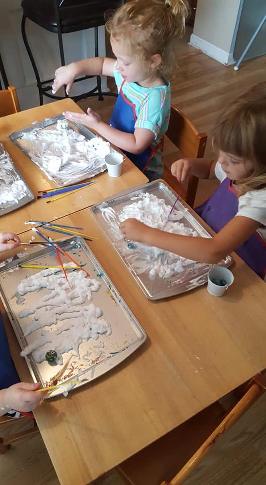 Children playing with shaving cream on baking sheets