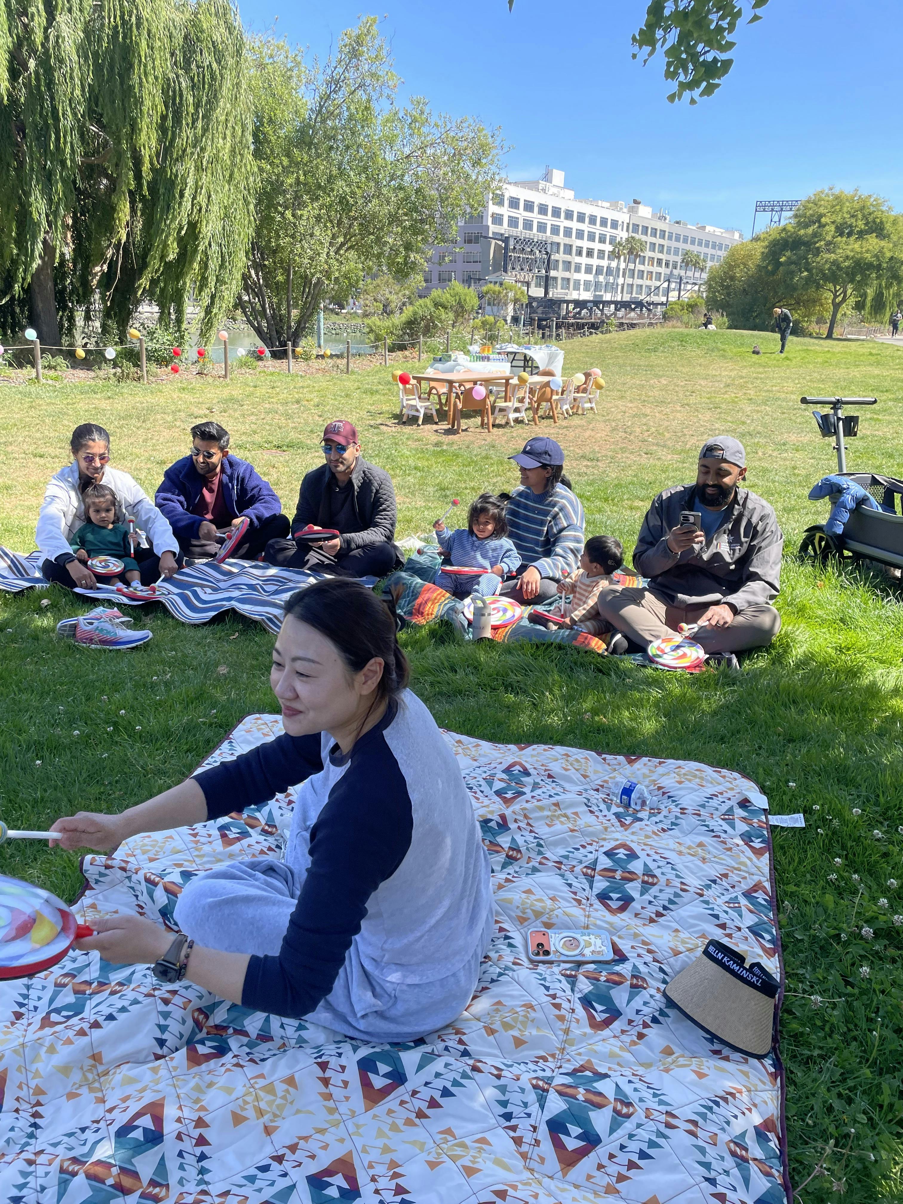 People picnicking with children on blankets in a grassy park