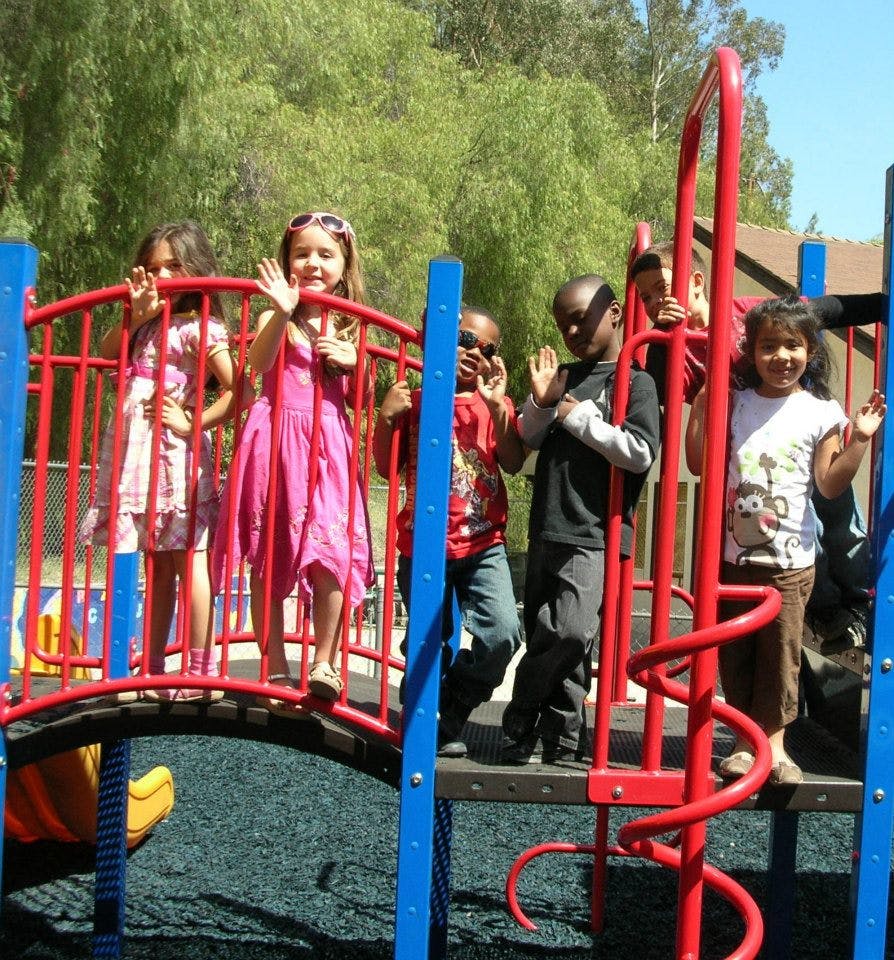 Children on a playground structure waving