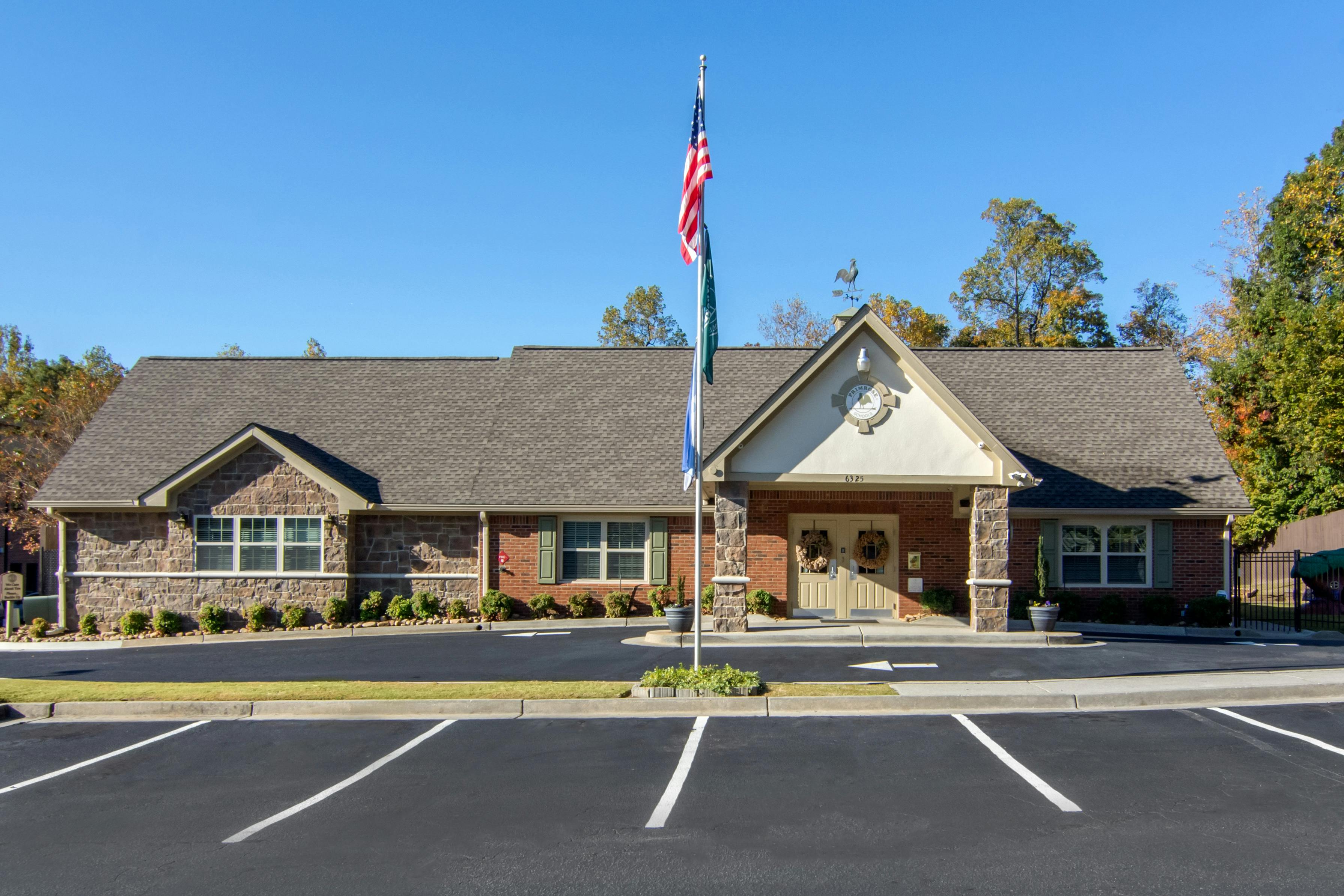 Brick building with a flagpole in front of the main entrance and a parking lot