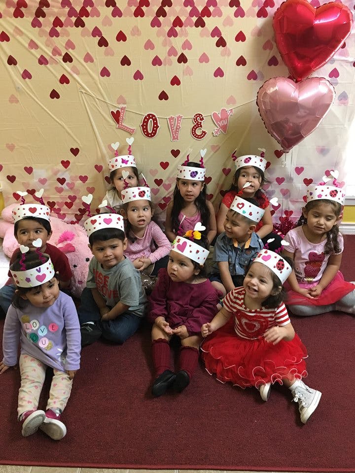 Group of children wearing paper crowns sitting on a red carpet