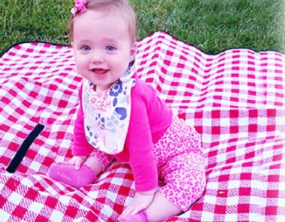 Child sitting on a red and white checkered blanket outdoors