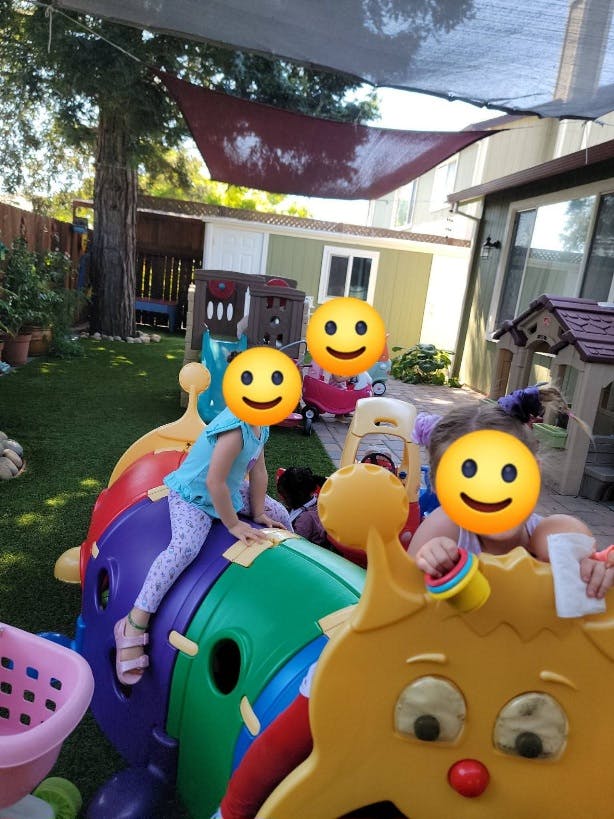 Children playing on a plastic caterpillar climbing toy in a backyard