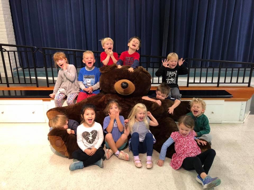Group of children sitting around a large stuffed bear