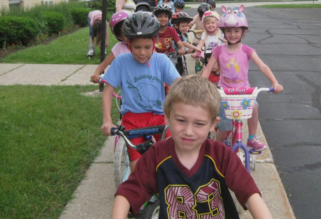 Group of children wearing helmets riding bicycles on a sidewalk