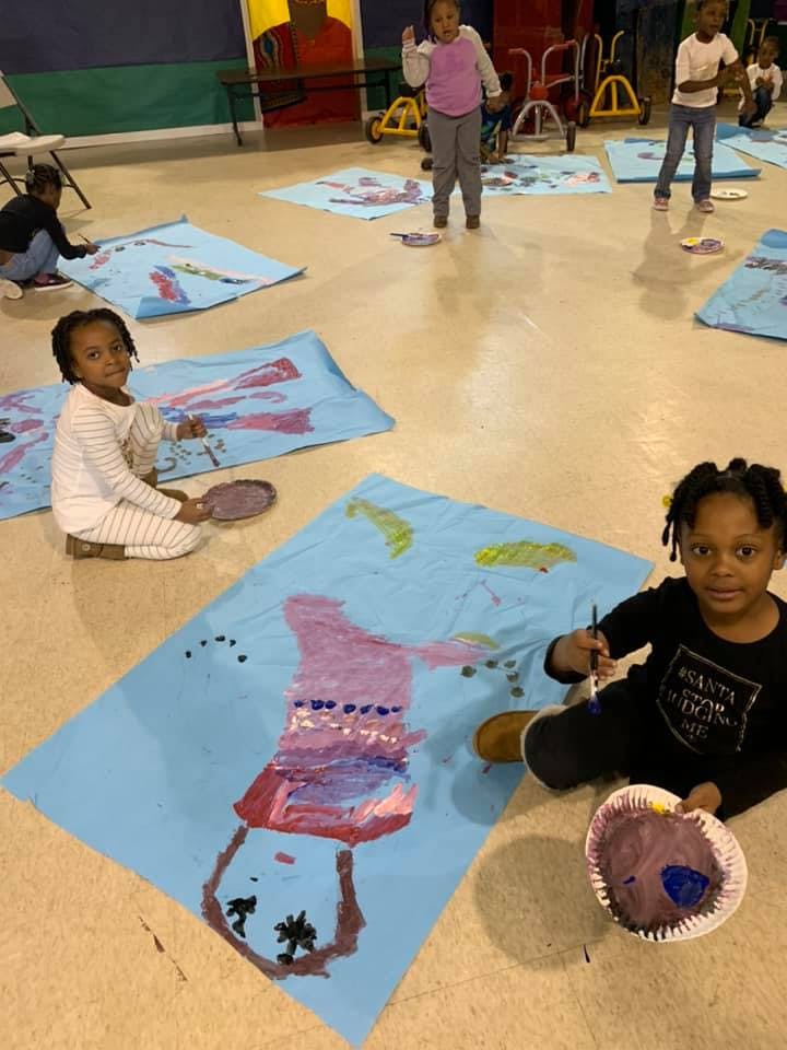 Children painting on large blue sheets on the floor