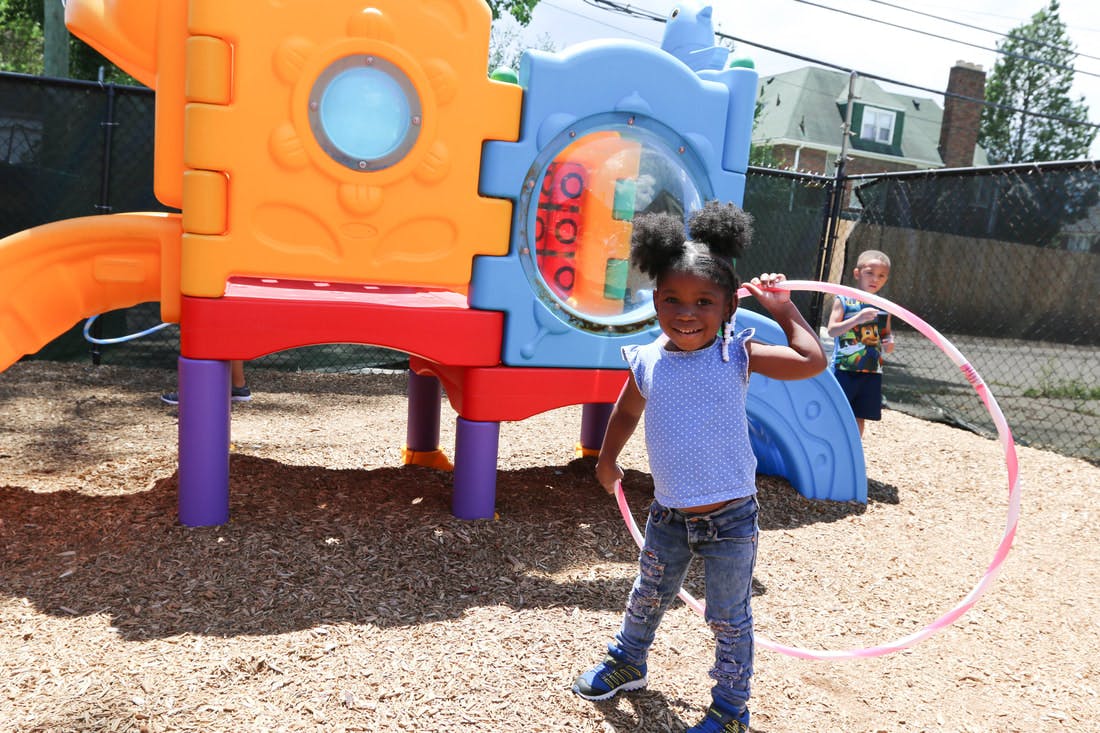 Child holding a hula hoop on a playground