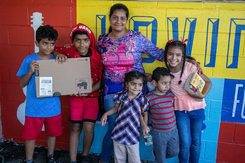 Adult and five children posing, two children holding a box