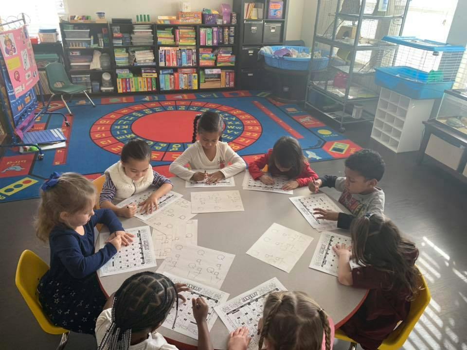 Children sitting around a table doing schoolwork in a classroom