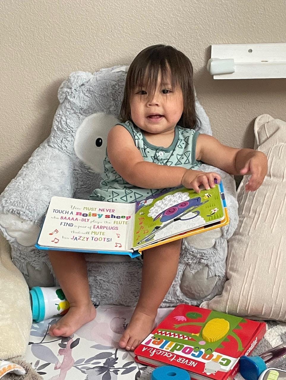 Child sitting in a plush chair holding an open book
