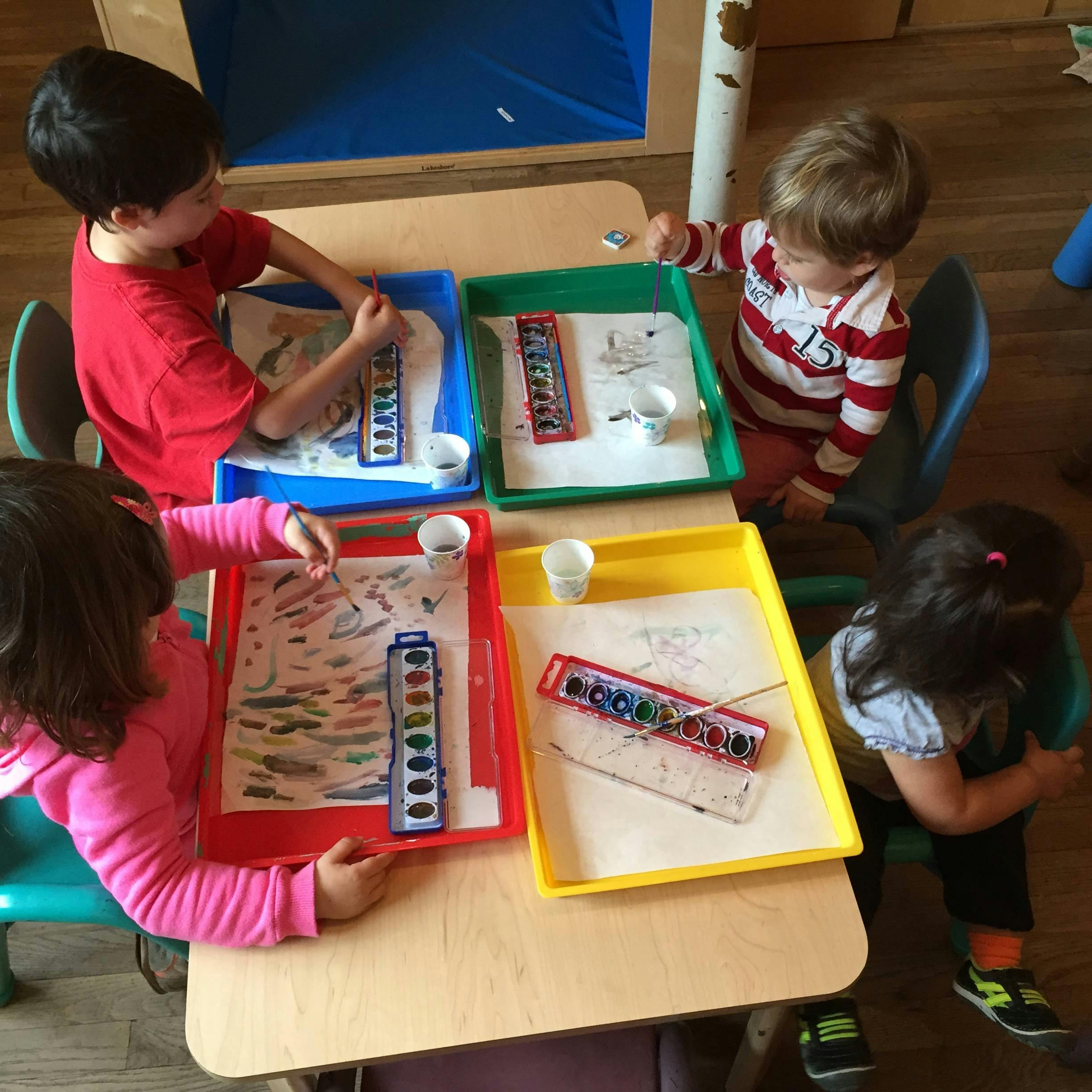 Children painting at a table in a classroom