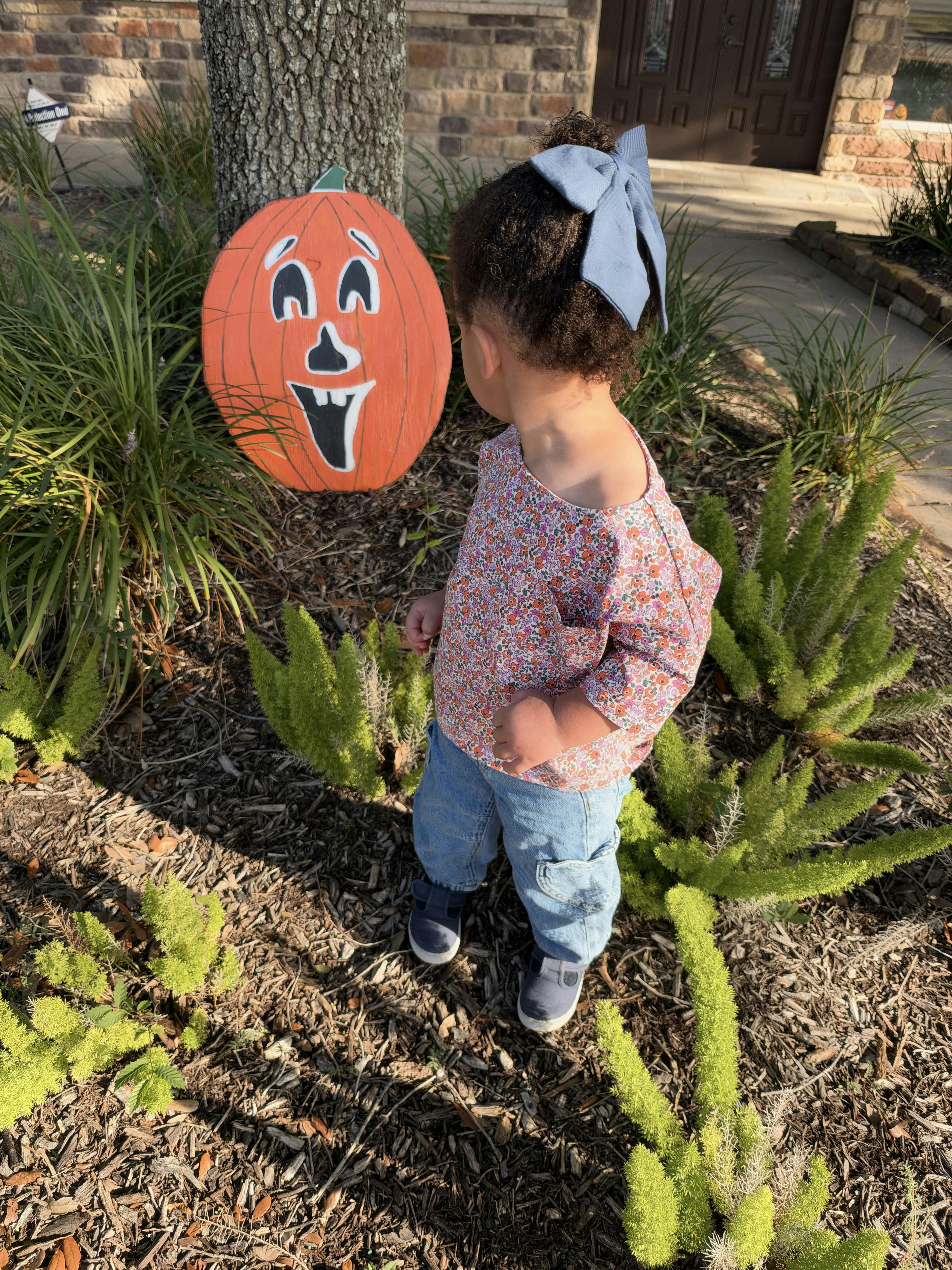 Child standing near a pumpkin decoration in a garden