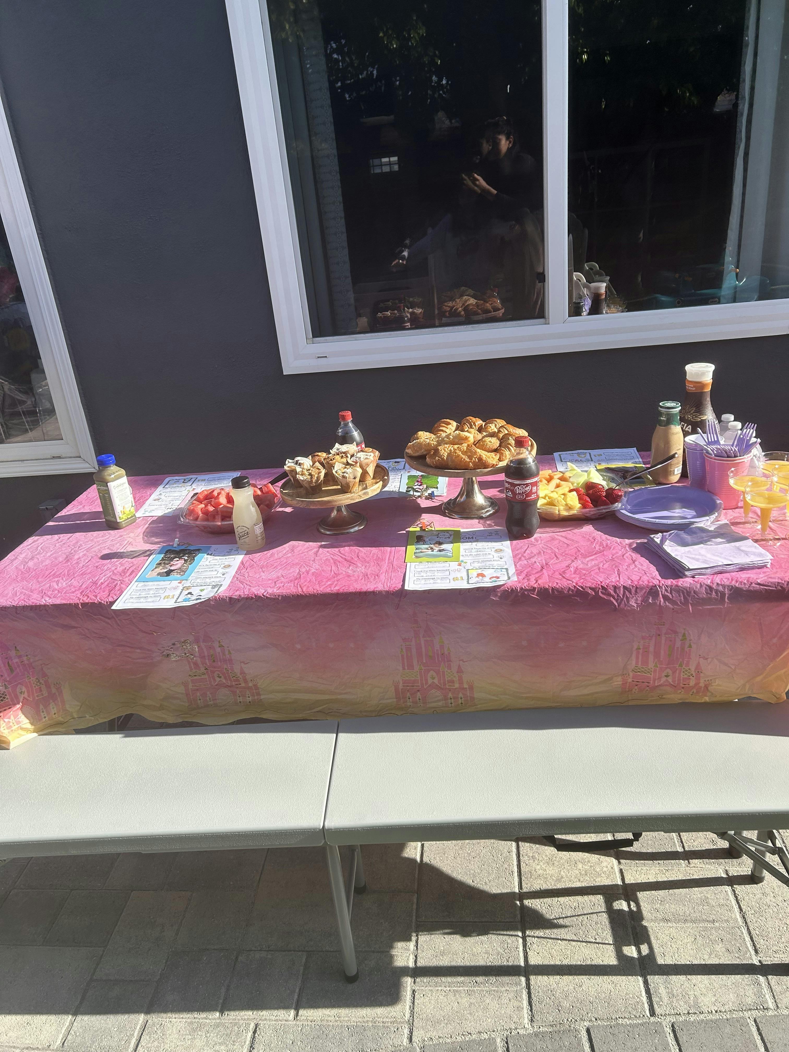 Table with pink tablecloth and various food items