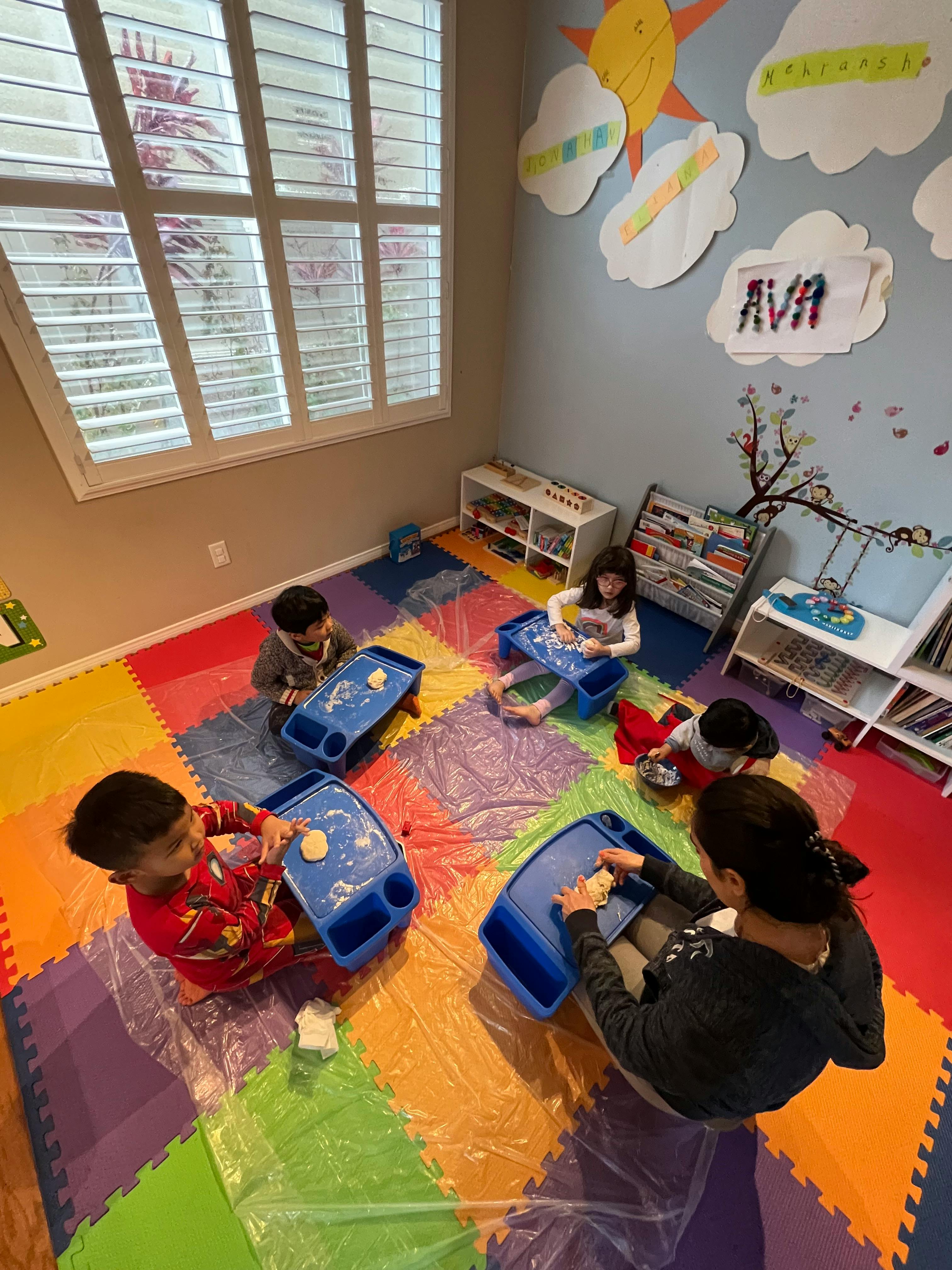 Adult and children sitting on floor with blue activity trays