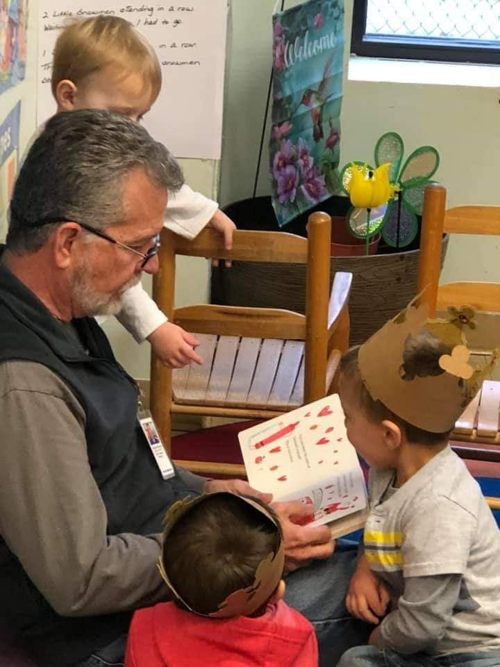 Adult reading a book to three children