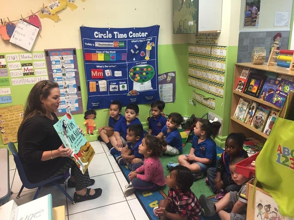 Person reading a book to a group of children in a classroom