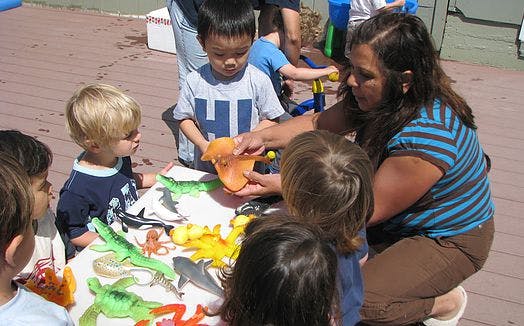 Adult and children playing with toys at a table