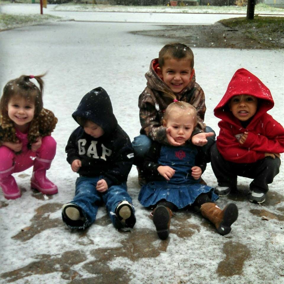 Five children sitting and crouching in light snow