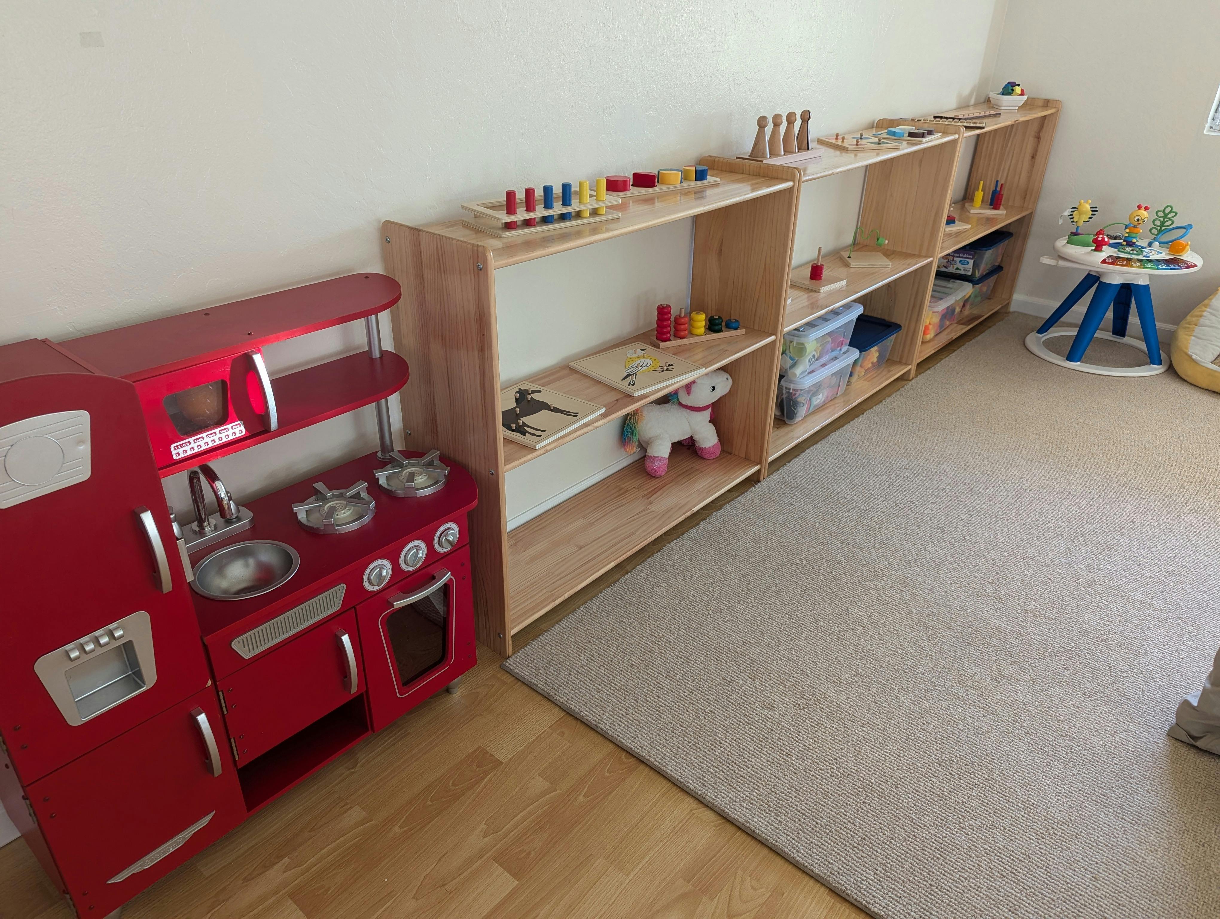 children's play kitchen and wooden shelves with toys in a classroom