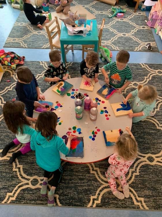 Children painting at a round table in a classroom