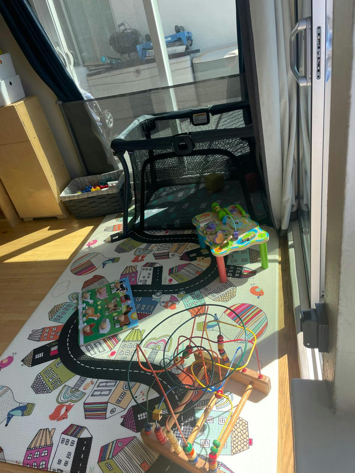 Playpen and toys on a playmat with a road design