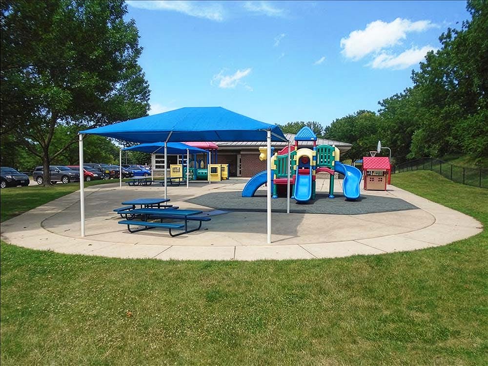 Playground with blue slides under blue awnings and picnic tables