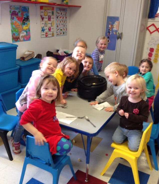Group of children gathered around a table in a classroom