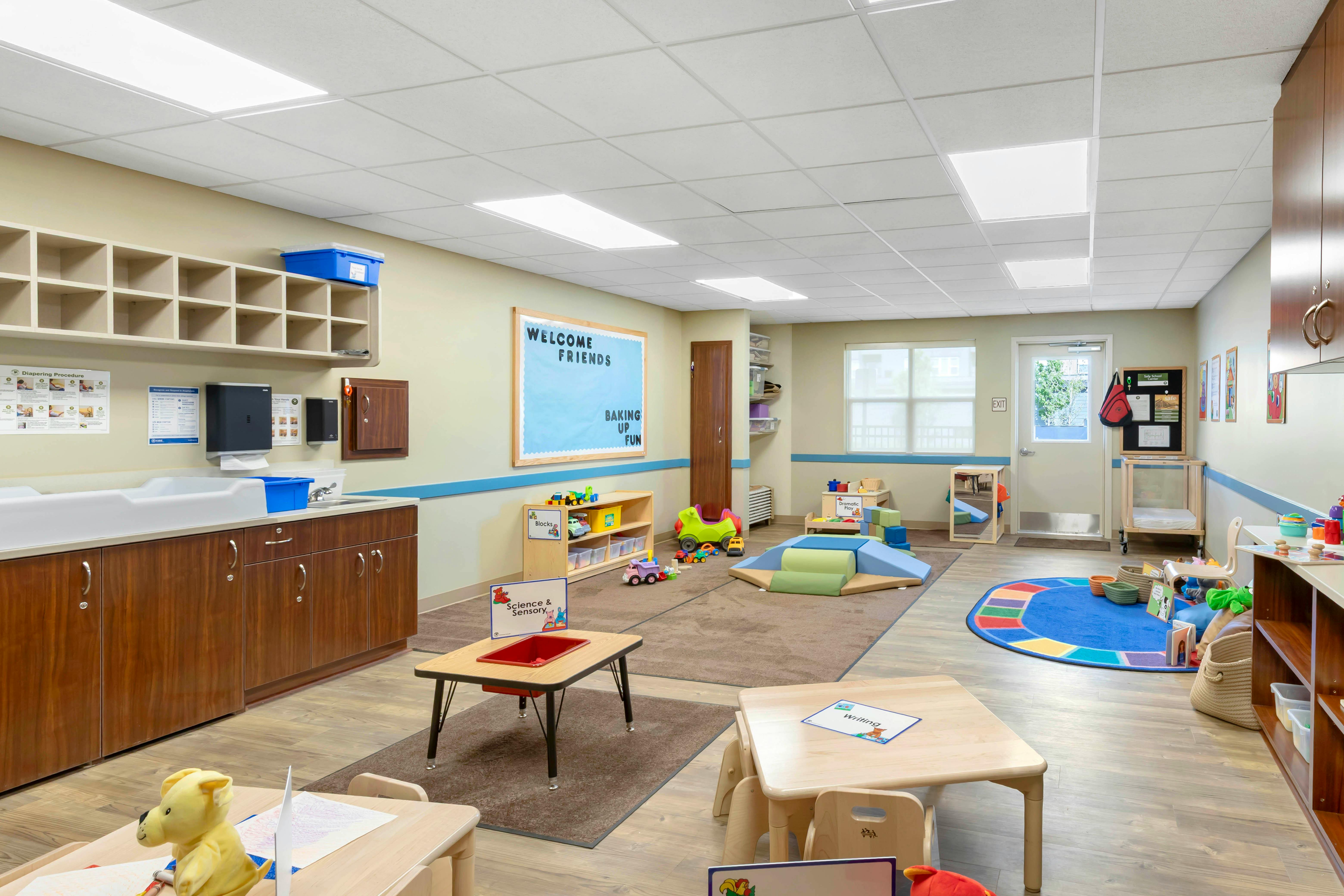 Classroom with play areas, changing table, and Welcome Friends bulletin board