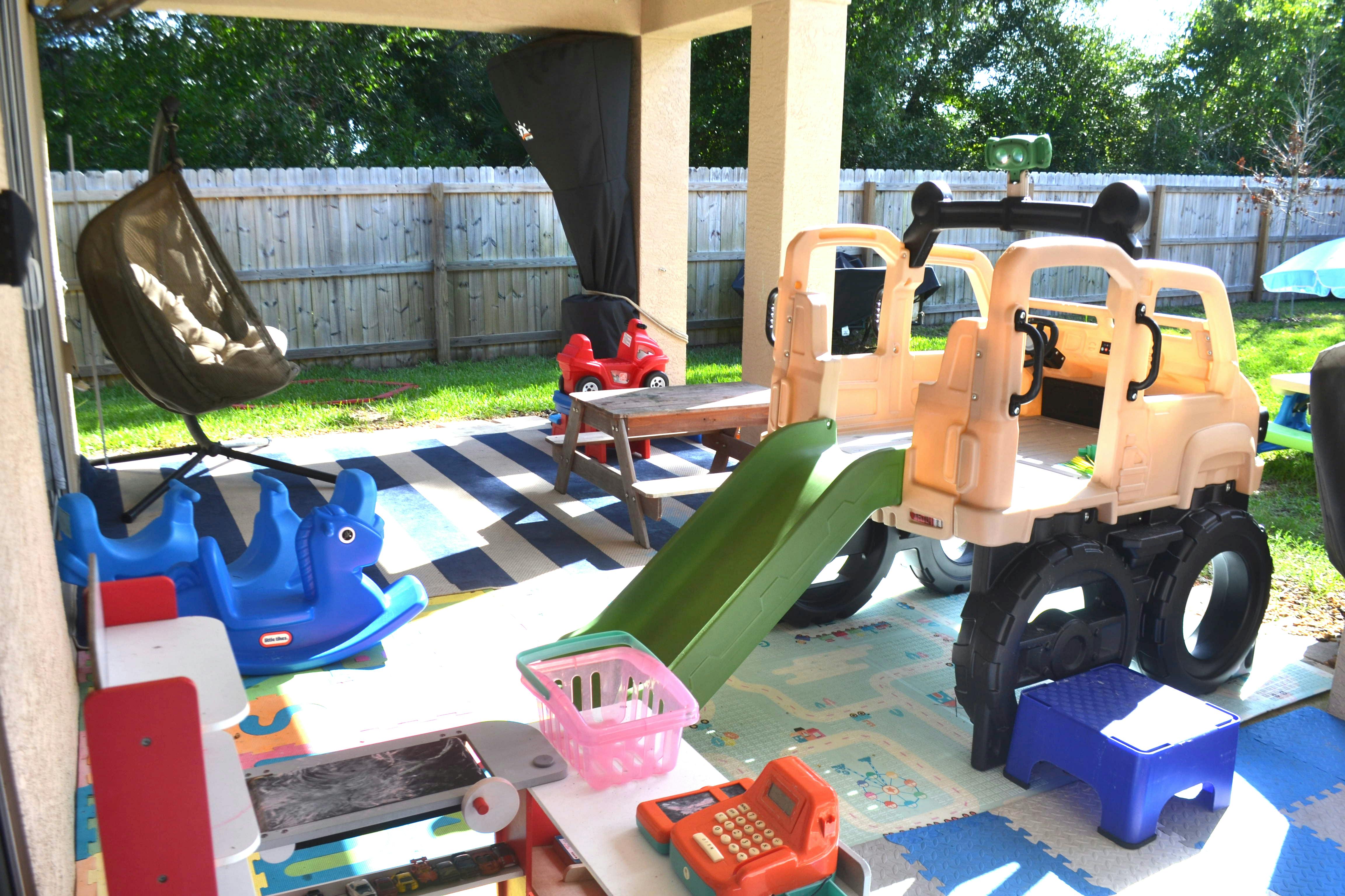 Outdoor play area with various toys including a ride-on truck and slide