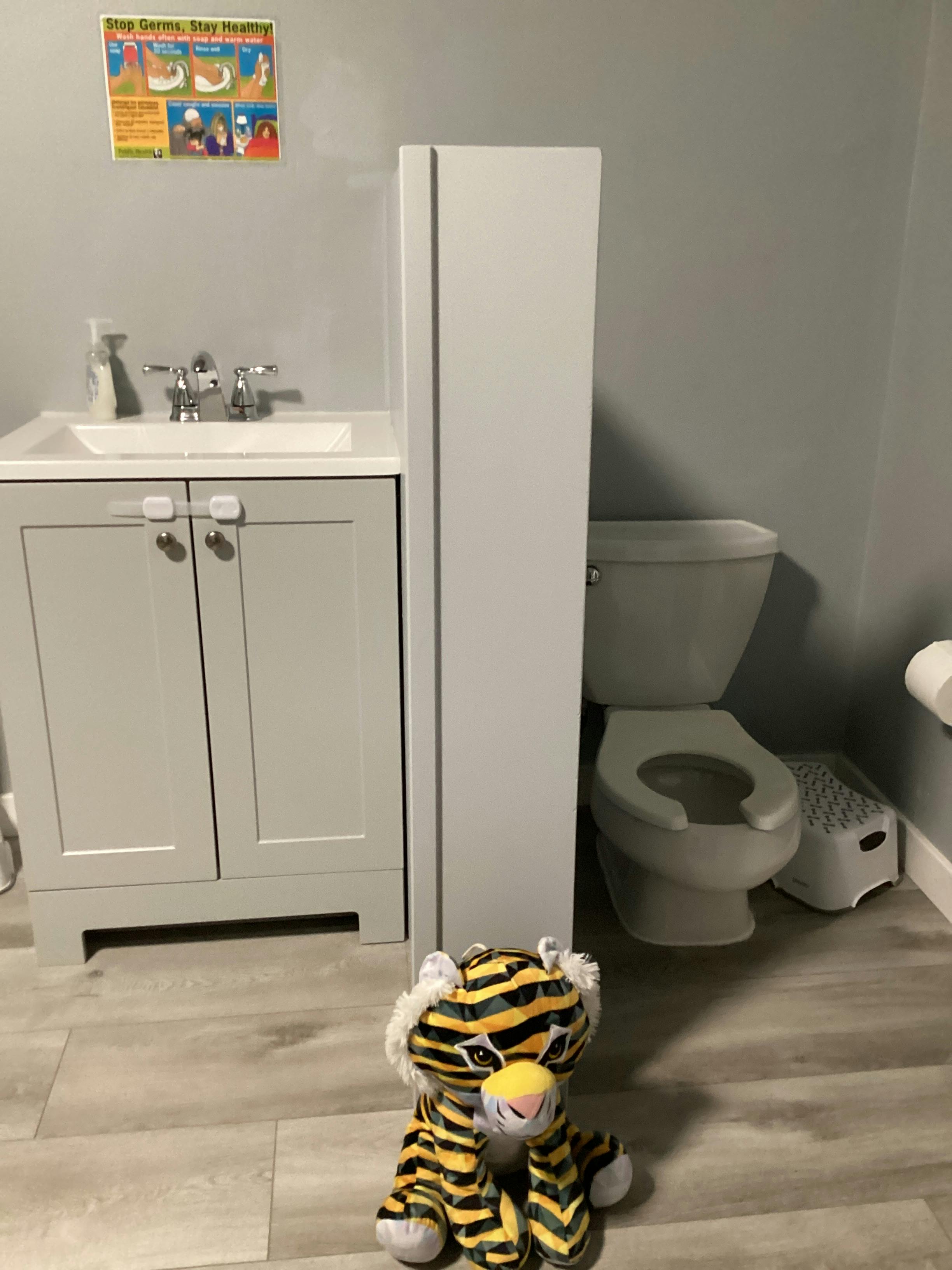 Bathroom with a sink, toilet, and a tiger stuffed animal on the floor