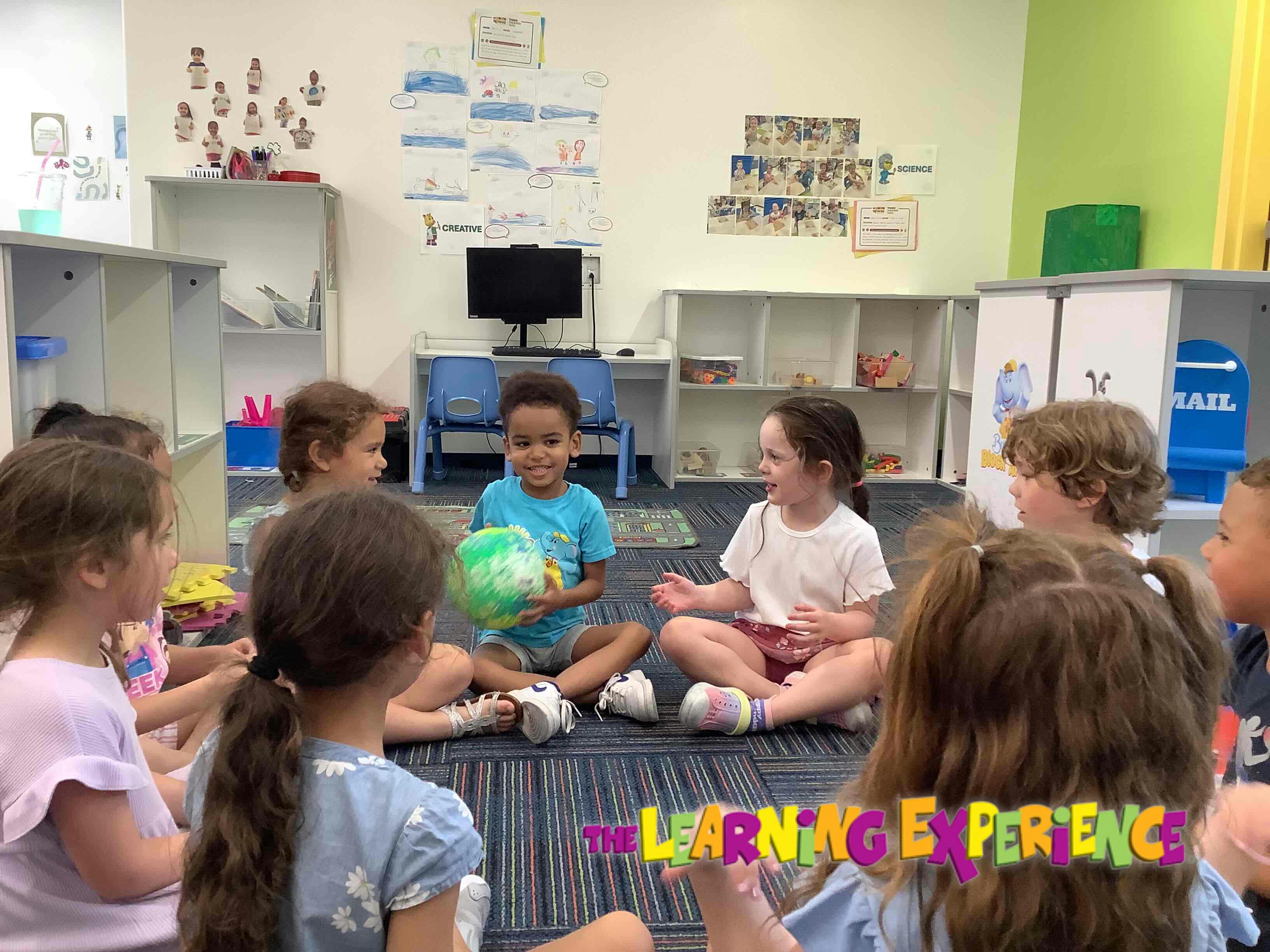 Children sitting in a circle on the floor, one child holding a globe
