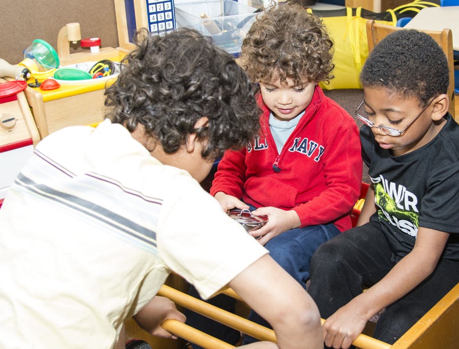 Three children looking at a small object held by one child