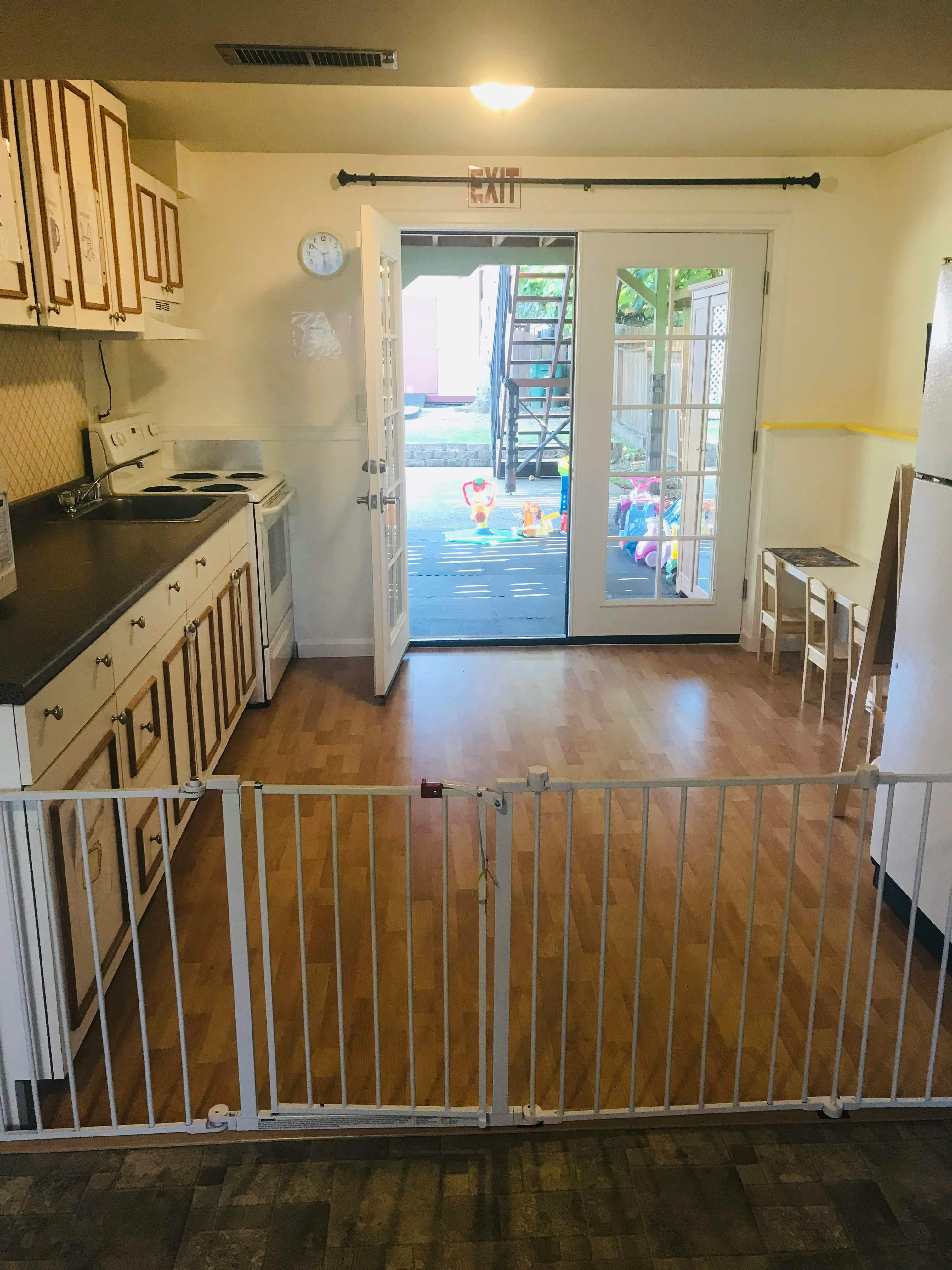 Kitchen with white cabinets, black counter, and open glass doors to outside
