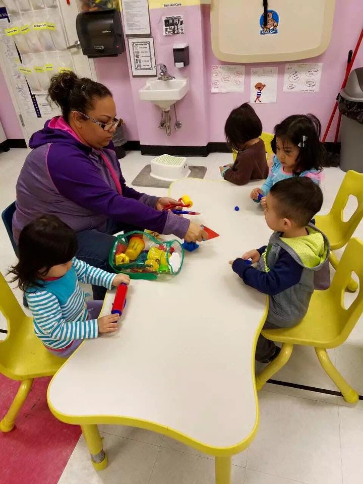 Person and three children playing with toys at a table