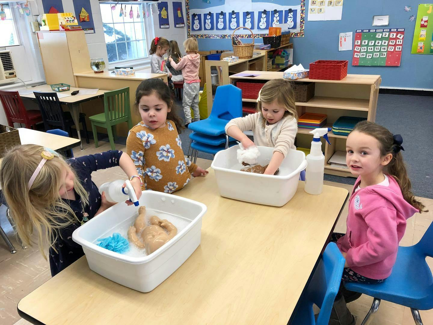 Children playing with water and toys in a classroom