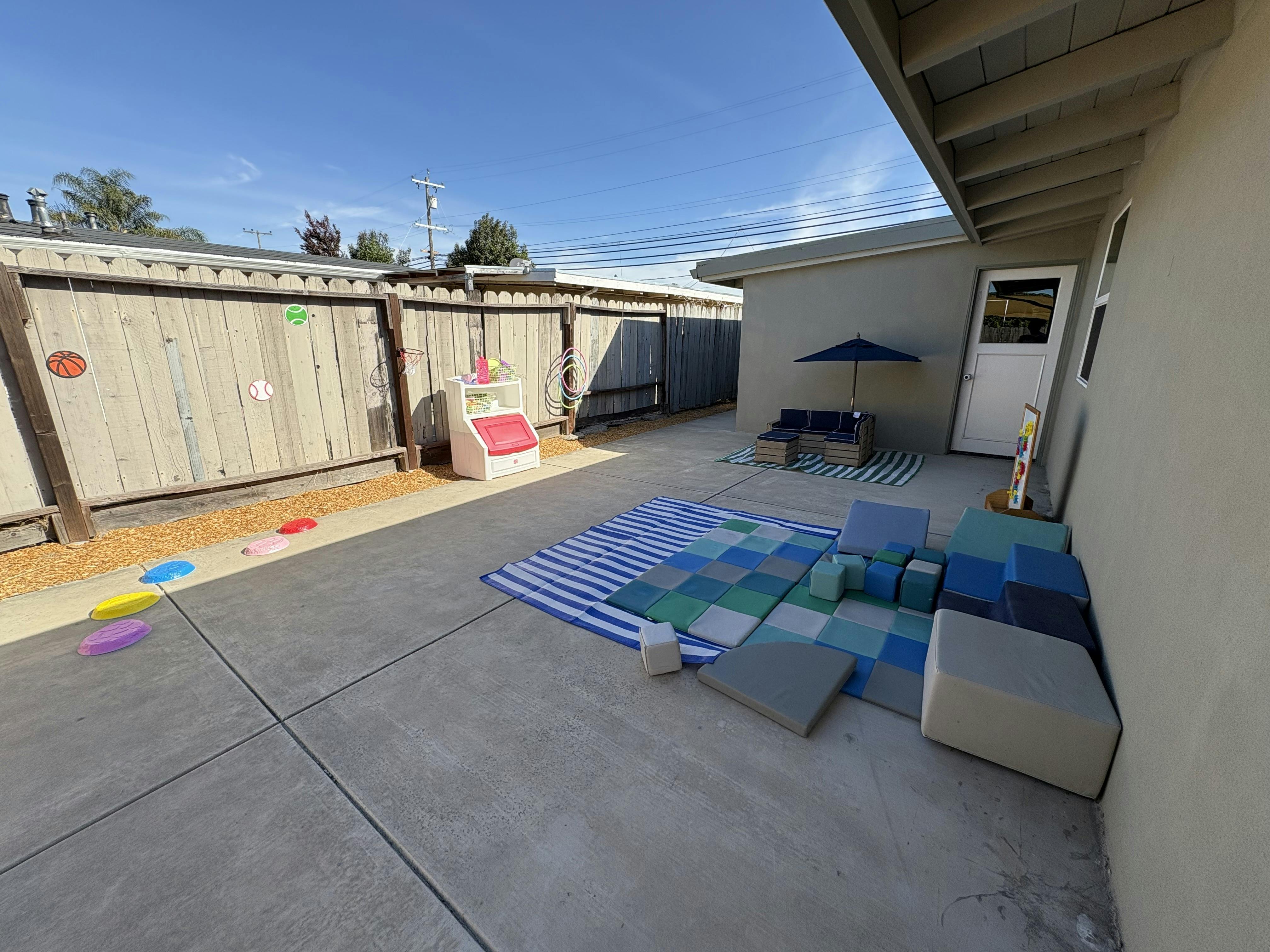 Outdoor play area with soft play mats, toy storage, and seating