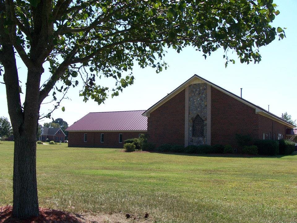 Brick building with a peaked roof and a tree in the foreground