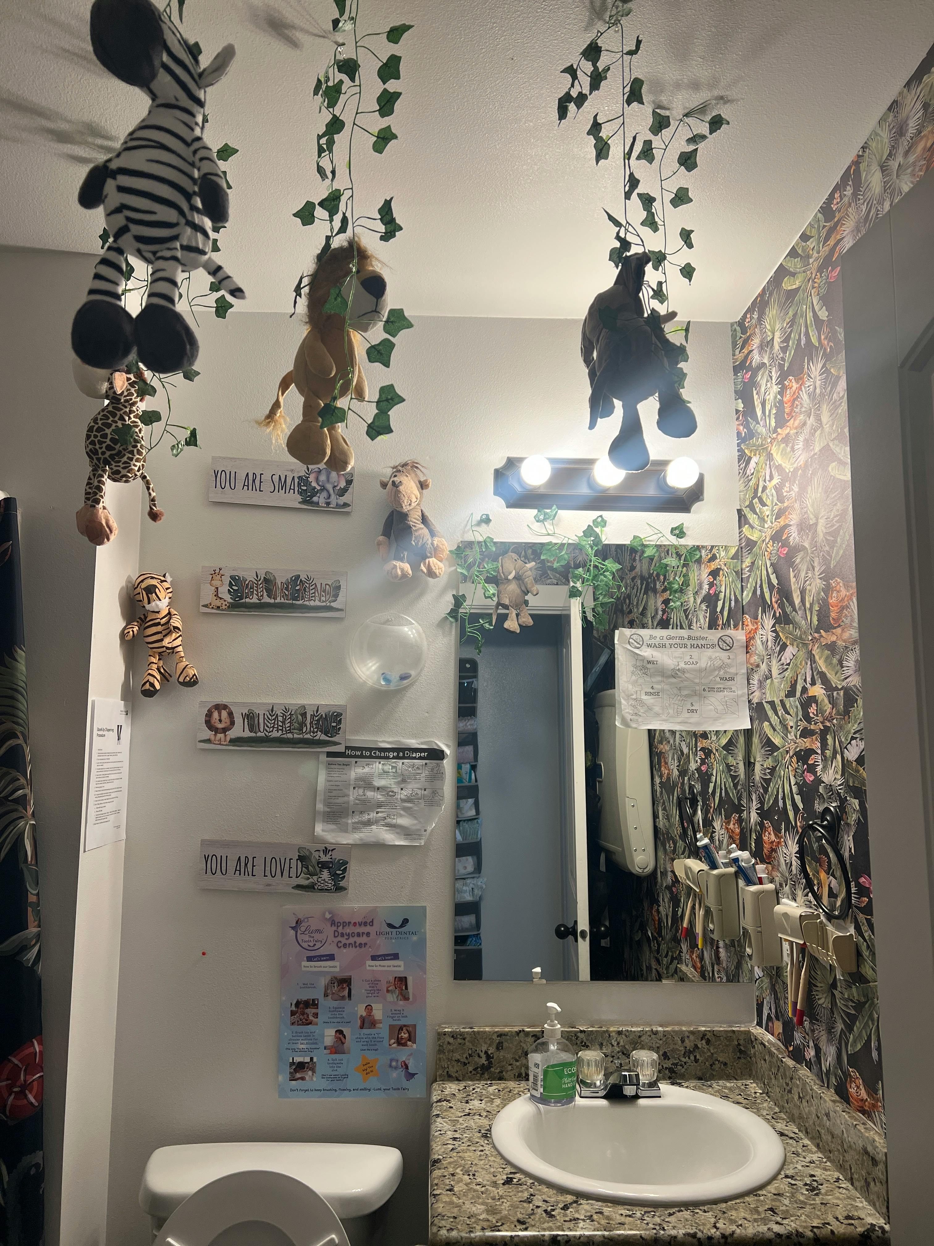 Plush jungle animal toys hanging from the ceiling in a restroom