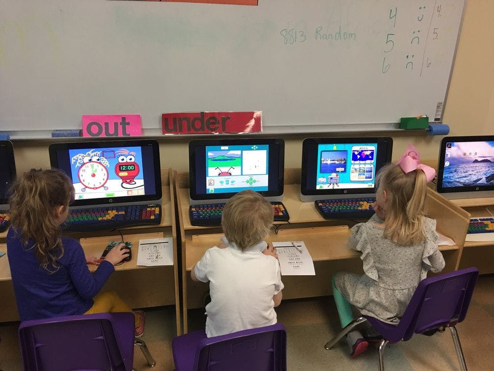 Three children using computers in a classroom