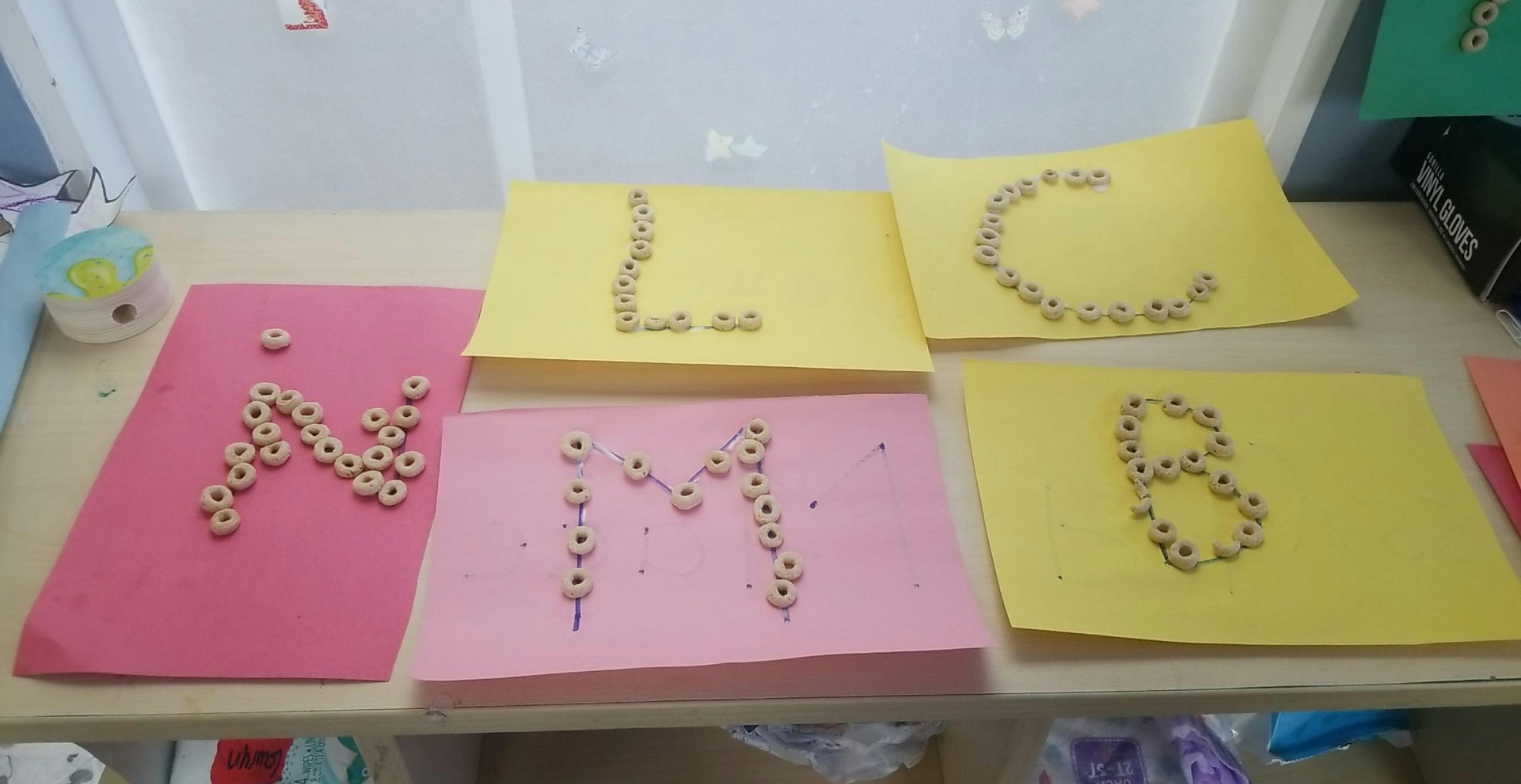 Letters of the alphabet made from cereal pieces on colored paper