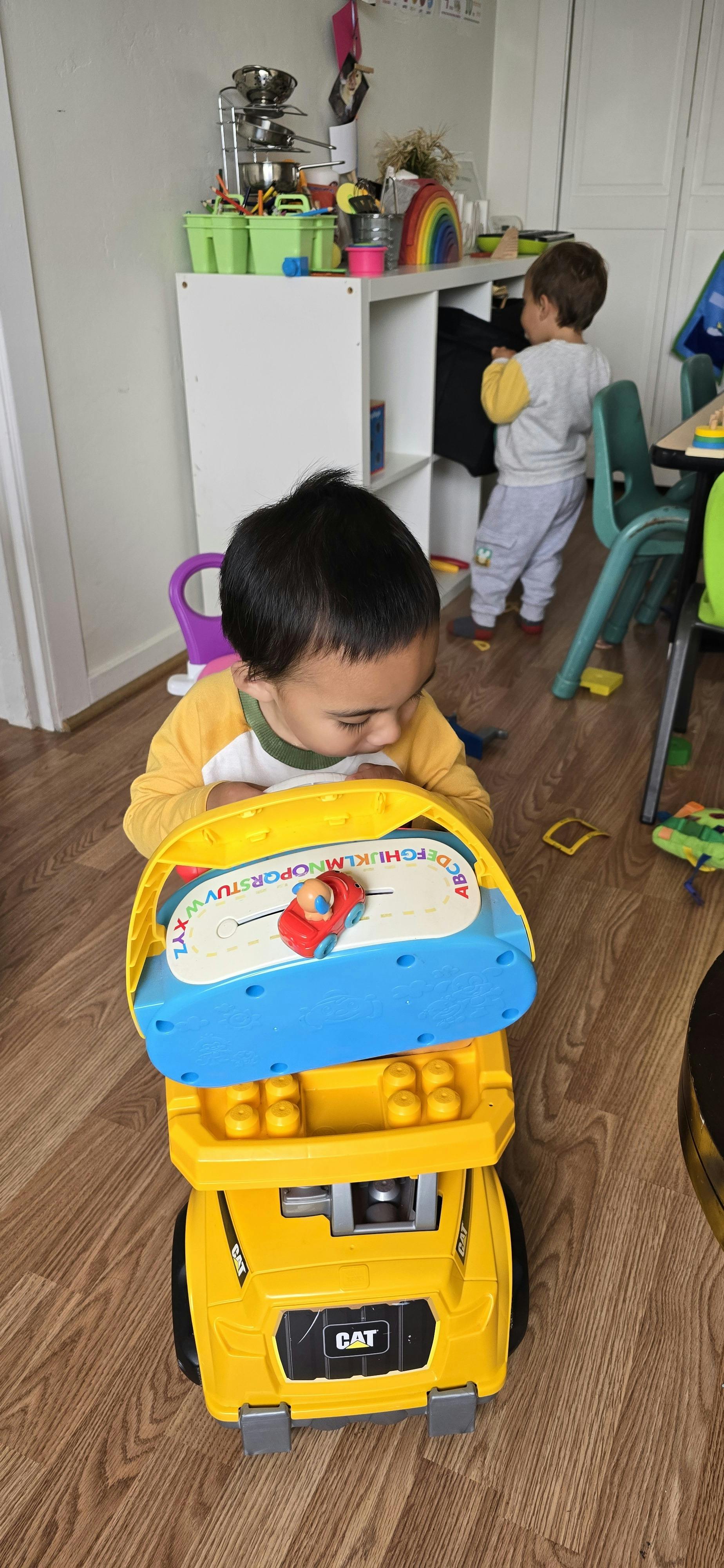 Child looking down at a toy truck with an alphabet track