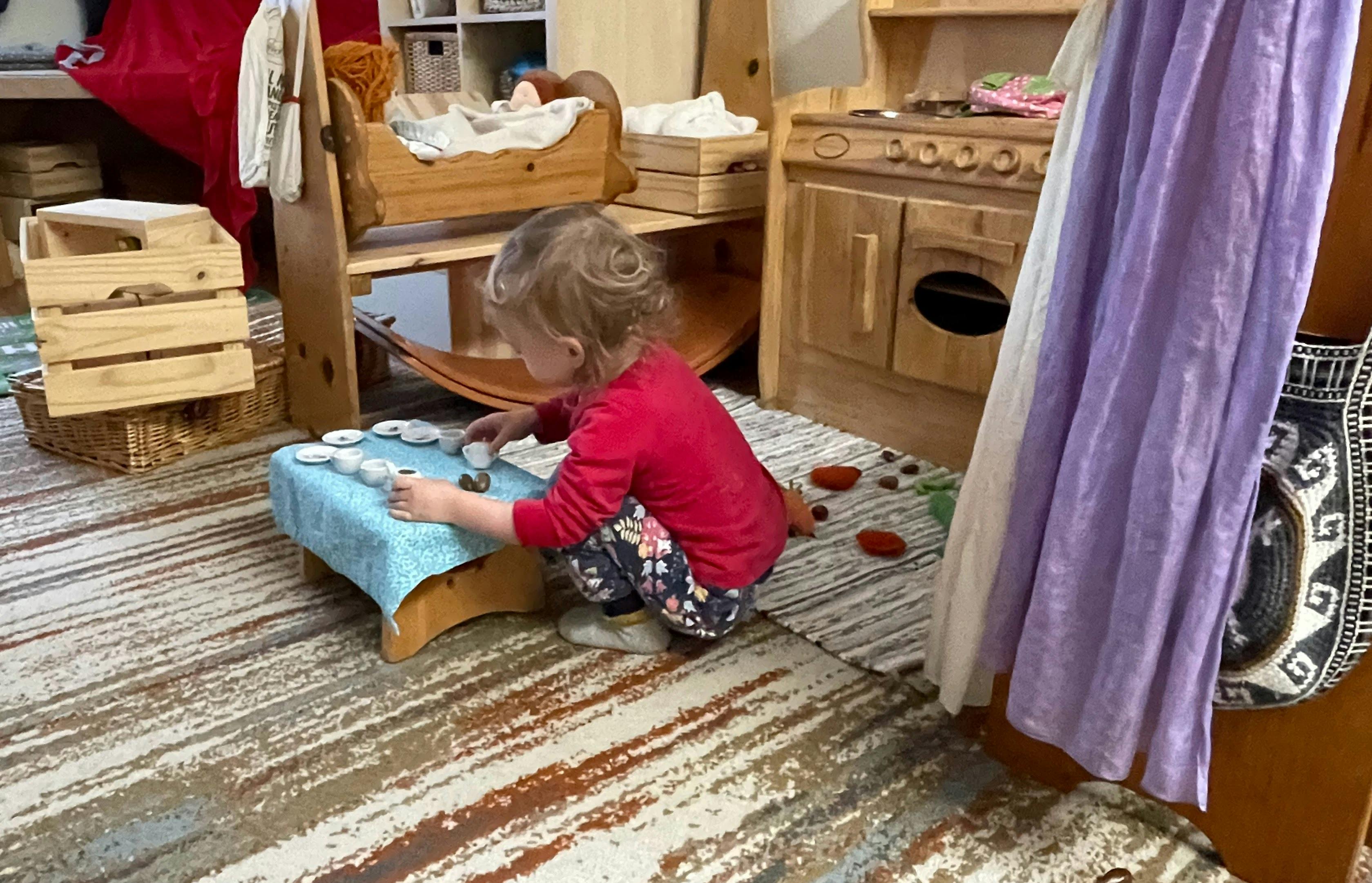 Child playing with objects on a small table