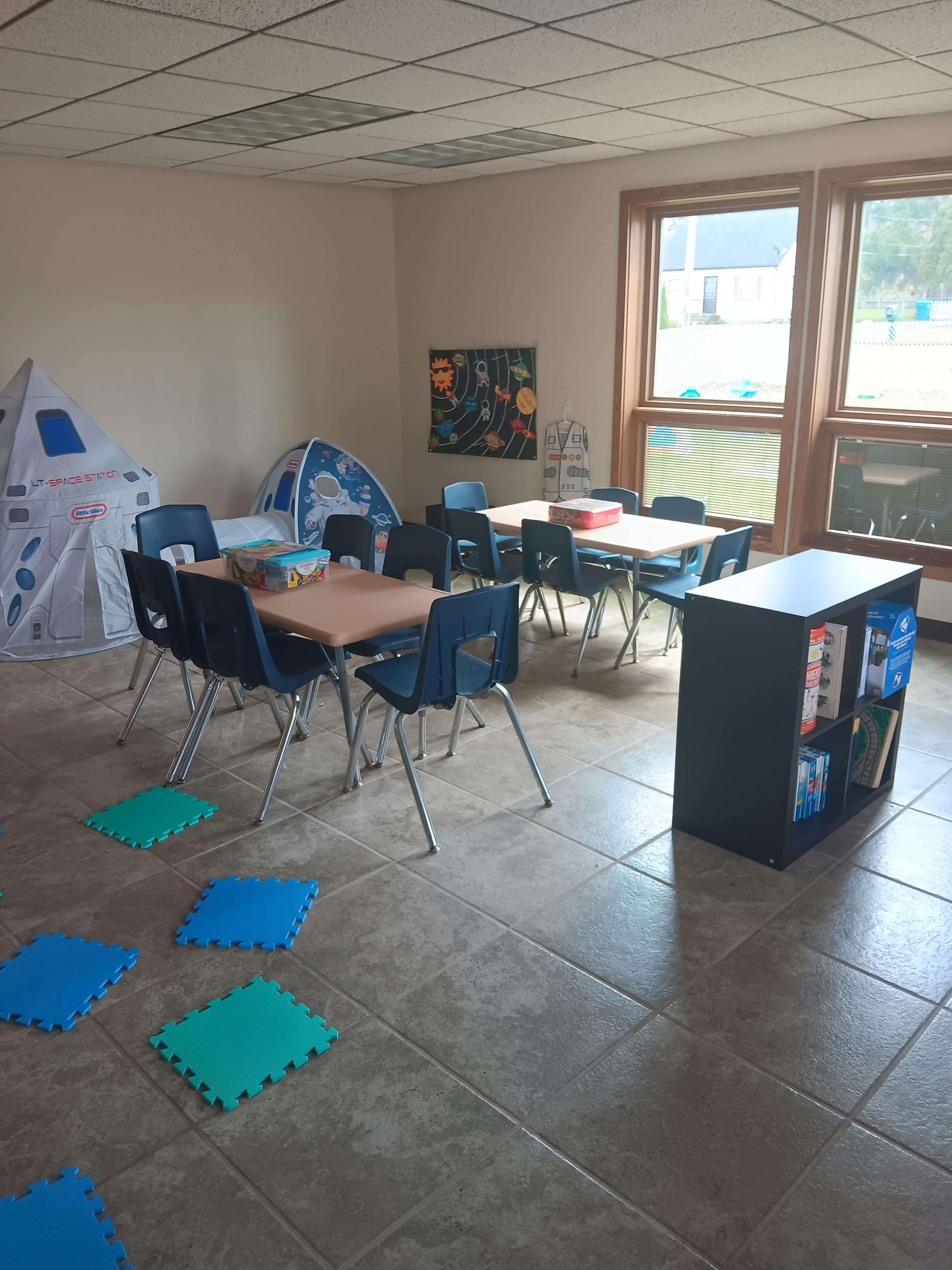 Classroom with tables, chairs, and play tents