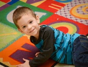 Child lying on a colorful alphabet rug